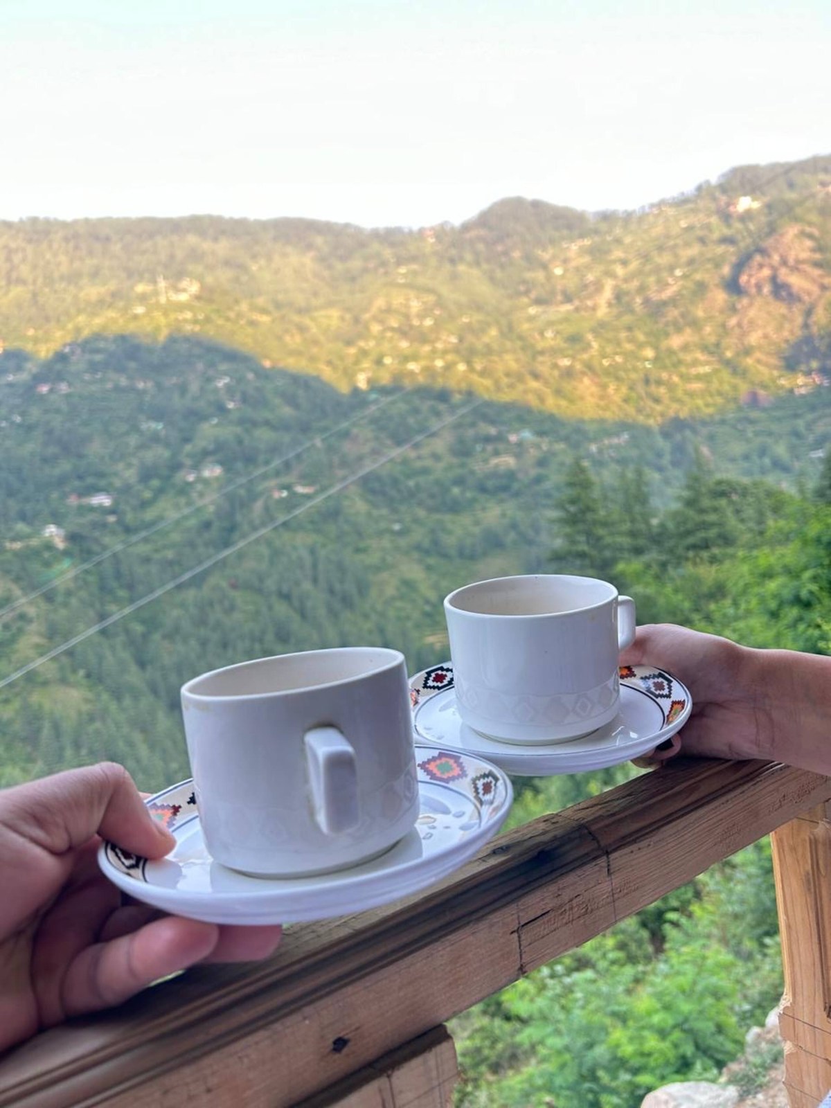 Two cups of tea on the railing with a mountain view